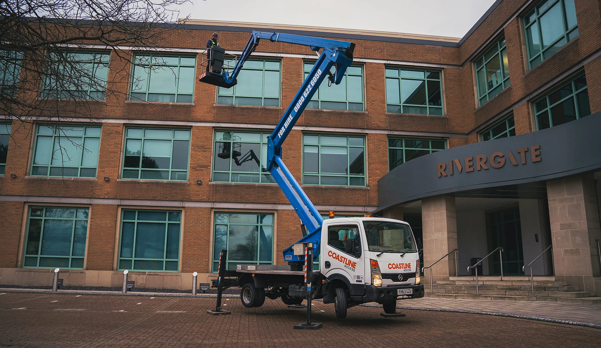 Picture of a coastline Cherry Picker Hire extending to reach the 3rd floor of a building