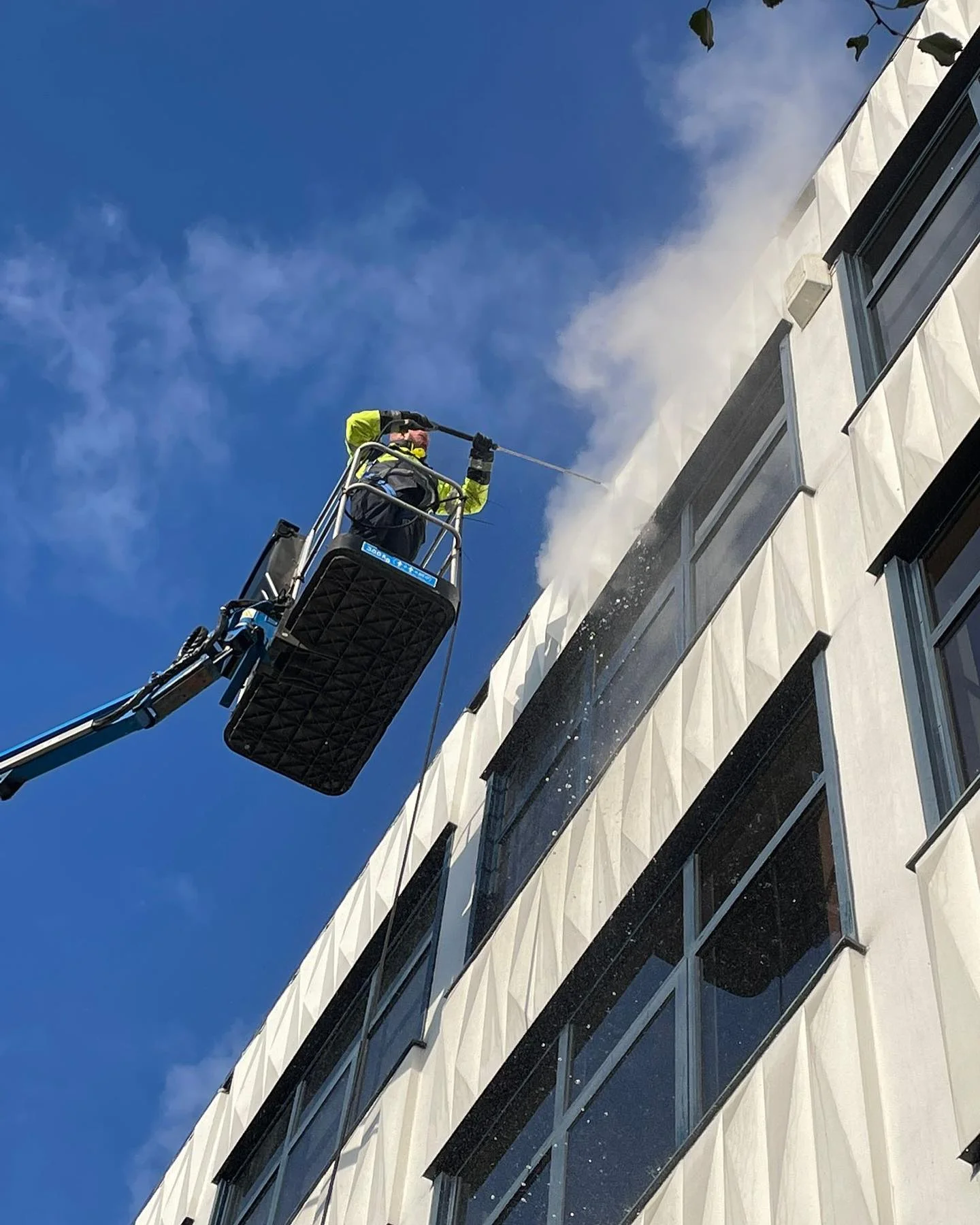 Picture of a coastline team member washing the 3rd floor of a building using a Cherry Picker Hire